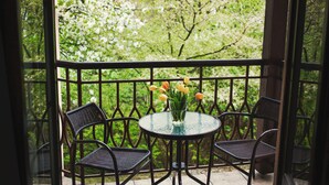 A balcony with a round glass table, four wicker chairs, and a vase with yellow tulips. - Hotel Eden (Kraków)