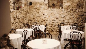A restaurant with stone walls and round tables covered with white tablecloths. - Hotel Eden (Kraków)