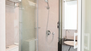 Ein modernes Badezimmer mit einer gläsernen Duschkabine, einer Toilette und einem Waschbecken mit Spiegel darüber.