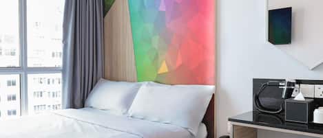 Una habitación de hotel con cama, un escritorio con teléfono y un diseño de pared geométrico y colorido.