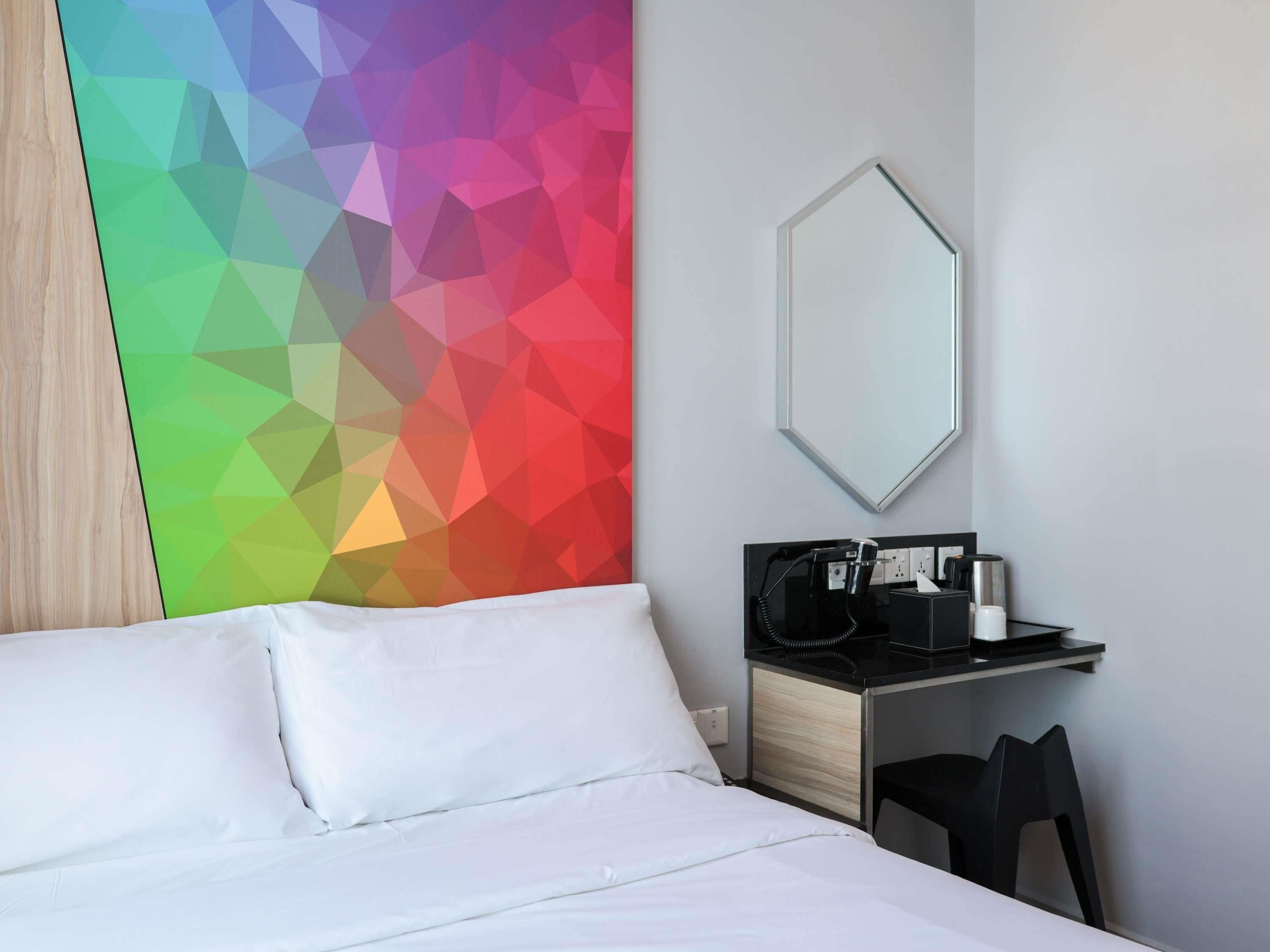 A hotel room with a bed, a desk with a telephone, and a mirror.