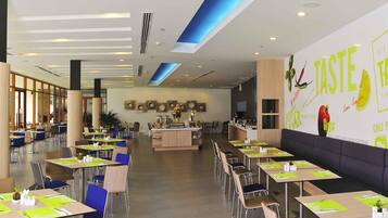 A modern dining area with tables and chairs, a central island with a bar, and a wall with food-related graphics.