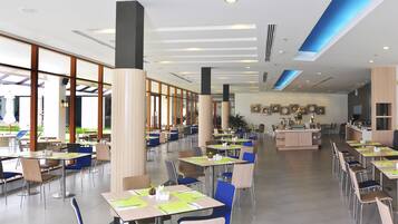 A spacious dining area with multiple tables and chairs, large windows, and a central counter.