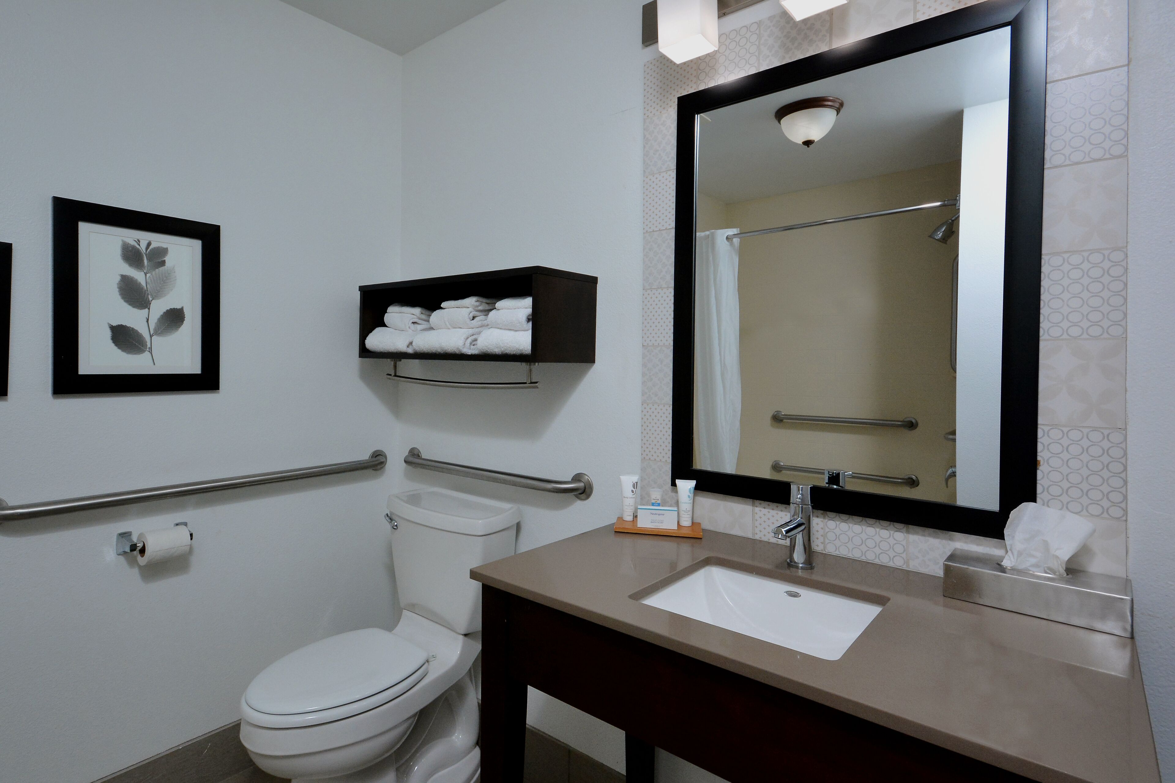 A modern bathroom with a white toilet, a sink with a mirror above it, and a towel rack above the sink.