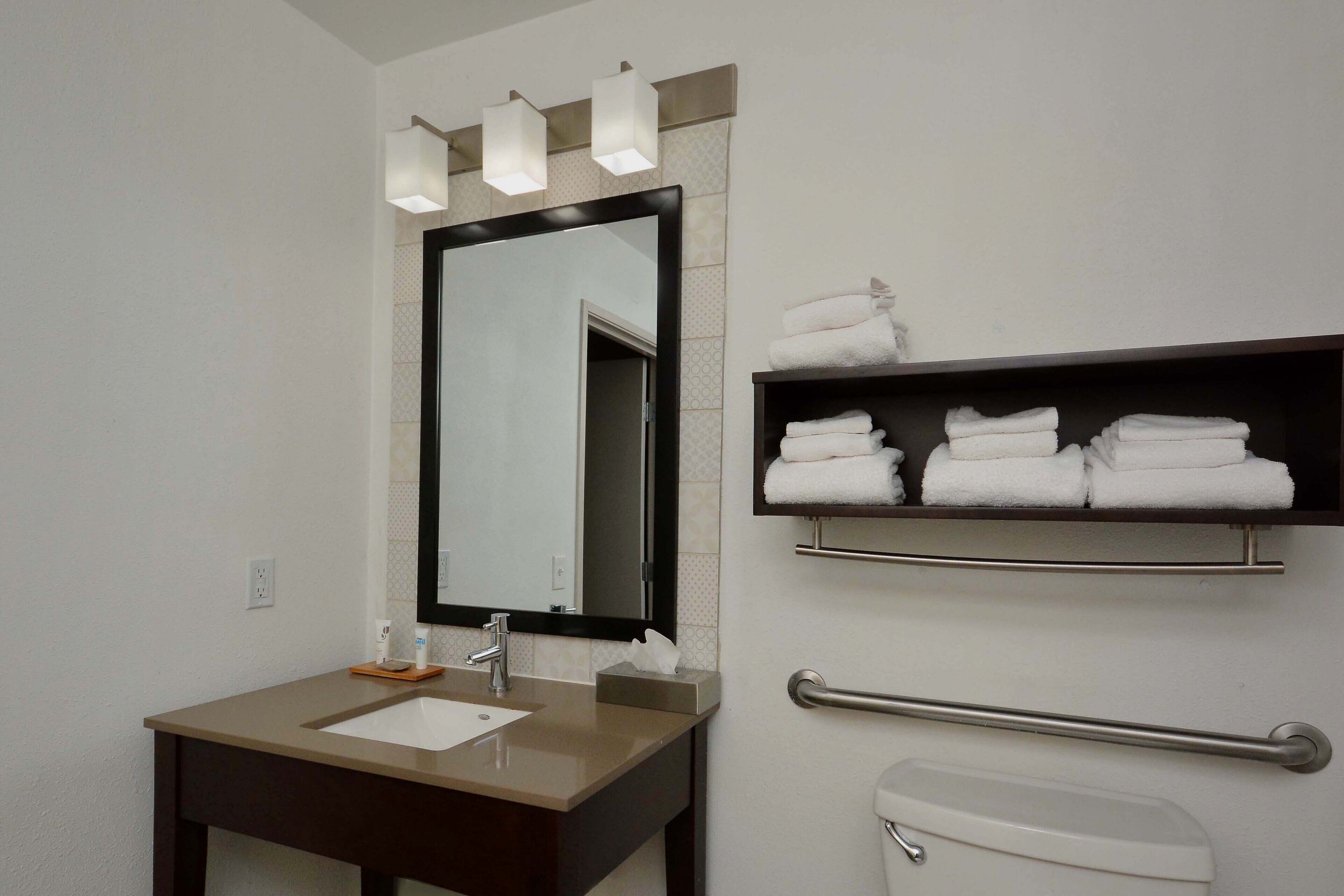 A bathroom with a sink, mirror, towel rack, and toilet.