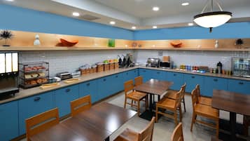 A modern kitchen with blue cabinets, wooden tables, and various kitchen appliances.