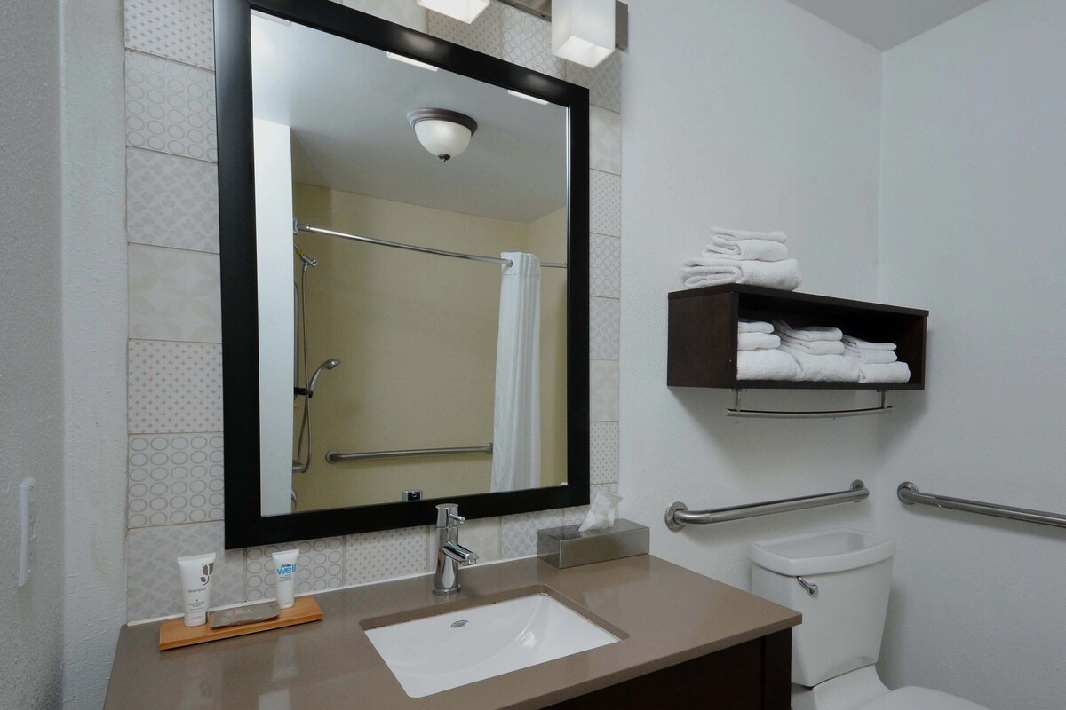Ein Badezimmer mit Waschbecken, Spiegel, Handtuchhalter und Toilette.