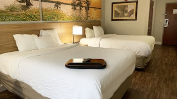 Habitación de hotel con dos camas, un cuadro de una puesta de sol sobre el agua, una fotografía enmarcada en la pared y un cabecero de madera.