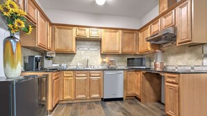A modern kitchen with wooden cabinets, a stainless steel refrigerator, a dishwasher, a microwave, and a coffee maker. - Days Inn & Suites by Wyndham Cabot (Cabot)