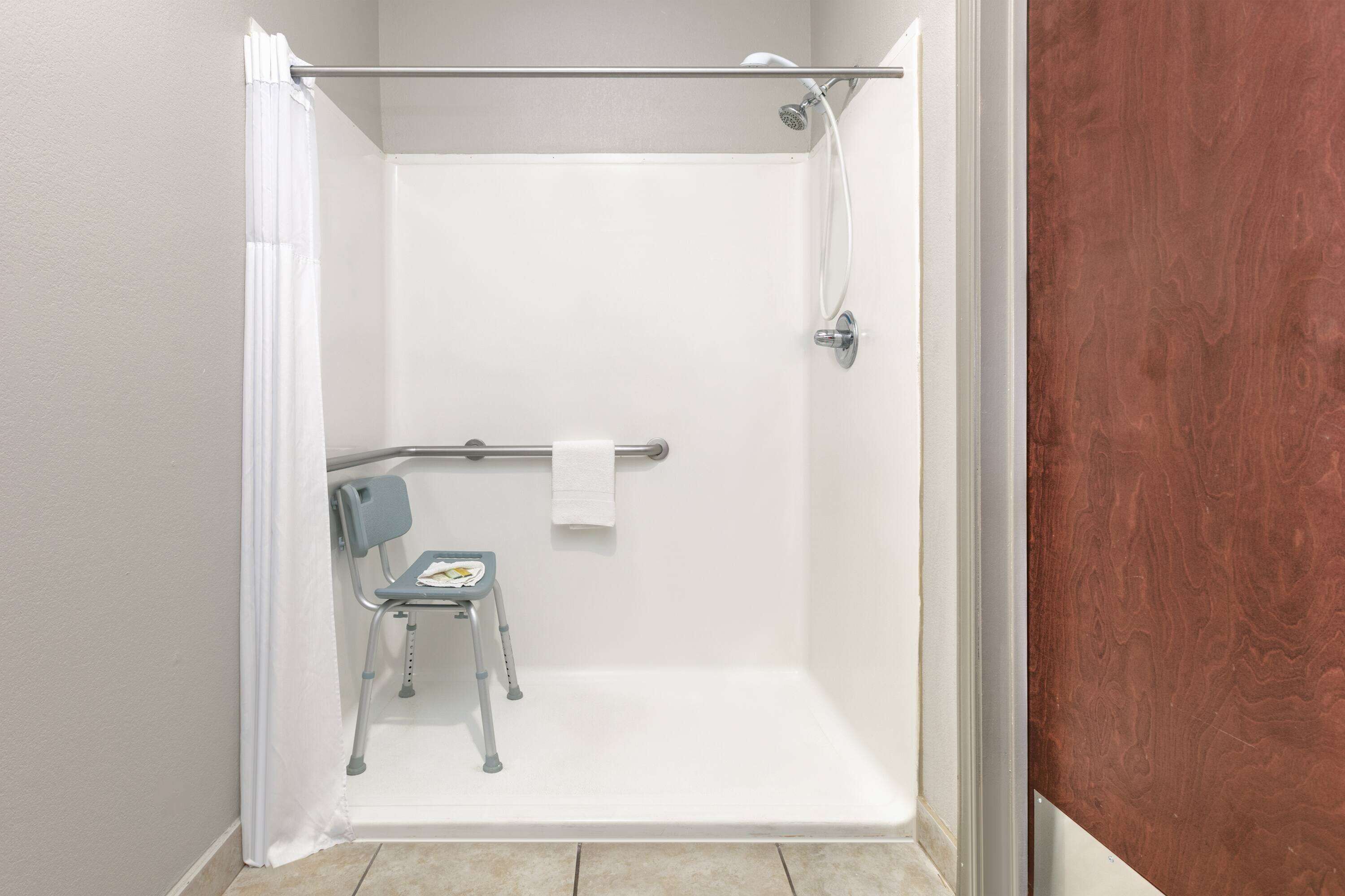 A shower area with a wheelchair, a towel, and a showerhead.