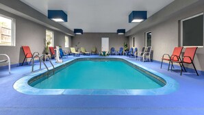 A swimming pool with blue tiles, surrounded by lounge chairs and a blue floor. - Days Inn & Suites by Wyndham Cabot (Cabot)