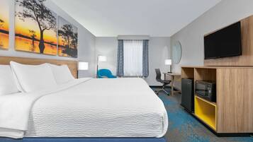 Una habitación de hotel con una cama grande, un escritorio con ordenador, televisión y obras de arte en las paredes.