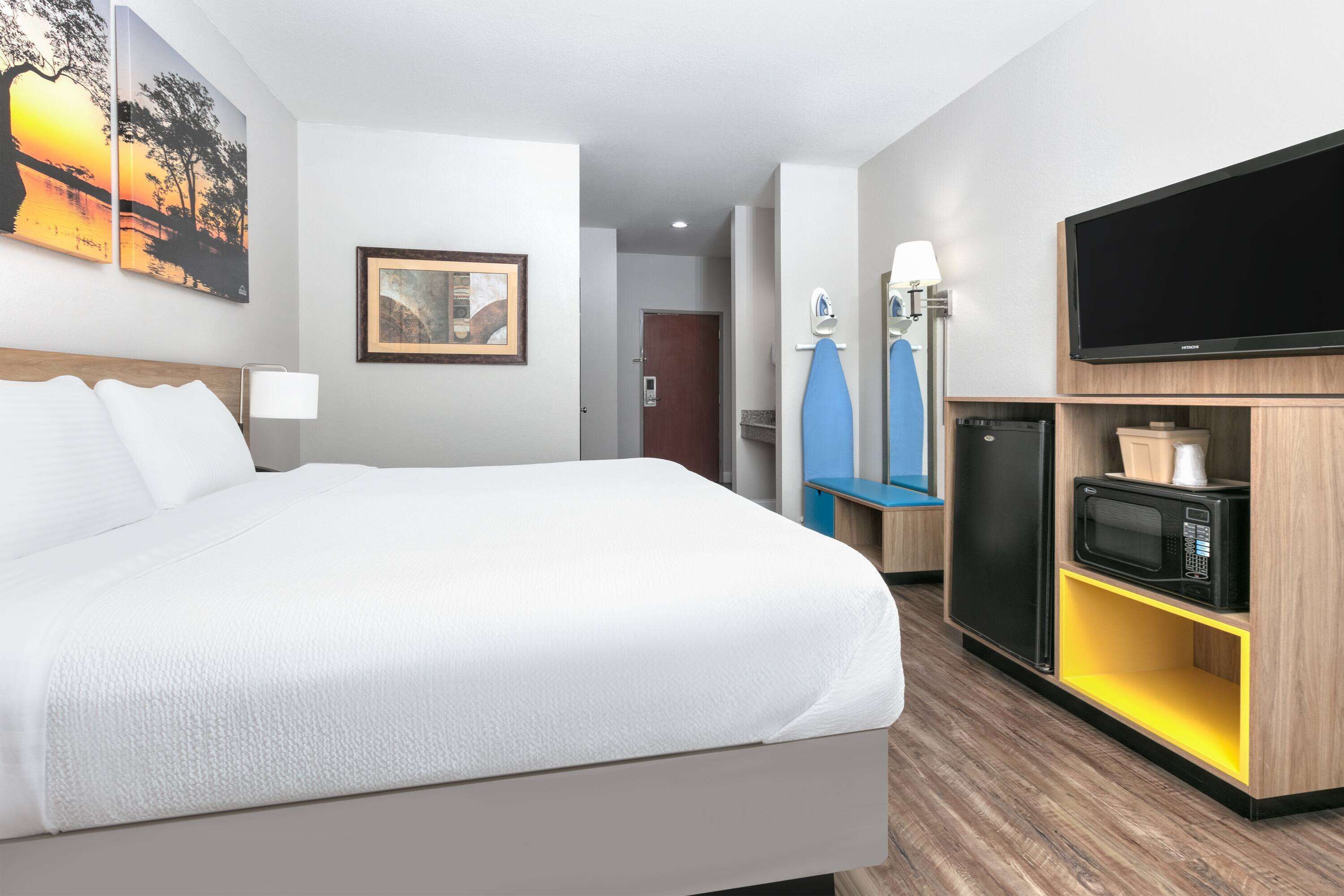 Hotellihuone, jossa on suuri sänky, taulutelevisio, mikroaaltouuni ja pieni keittonurkkaus.