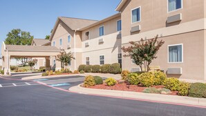 A multi-story hotel with a covered entrance, landscaped gardens, and a parking area with handicapped accessibility. - Days Inn & Suites by Wyndham Cabot (Cabot)