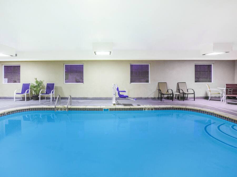 Una piscina interior con agua cristalina, rodeada de paredes y ventanas blancas.