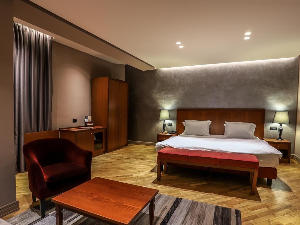 Ein Hotelzimmer mit einem Bett, einem Schreibtisch, einem Stuhl und einem Nachttisch mit Lampen.