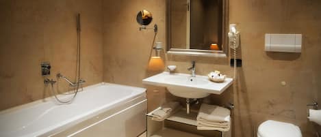 A modern bathroom with a bathtub, sink, mirror, and toilet.