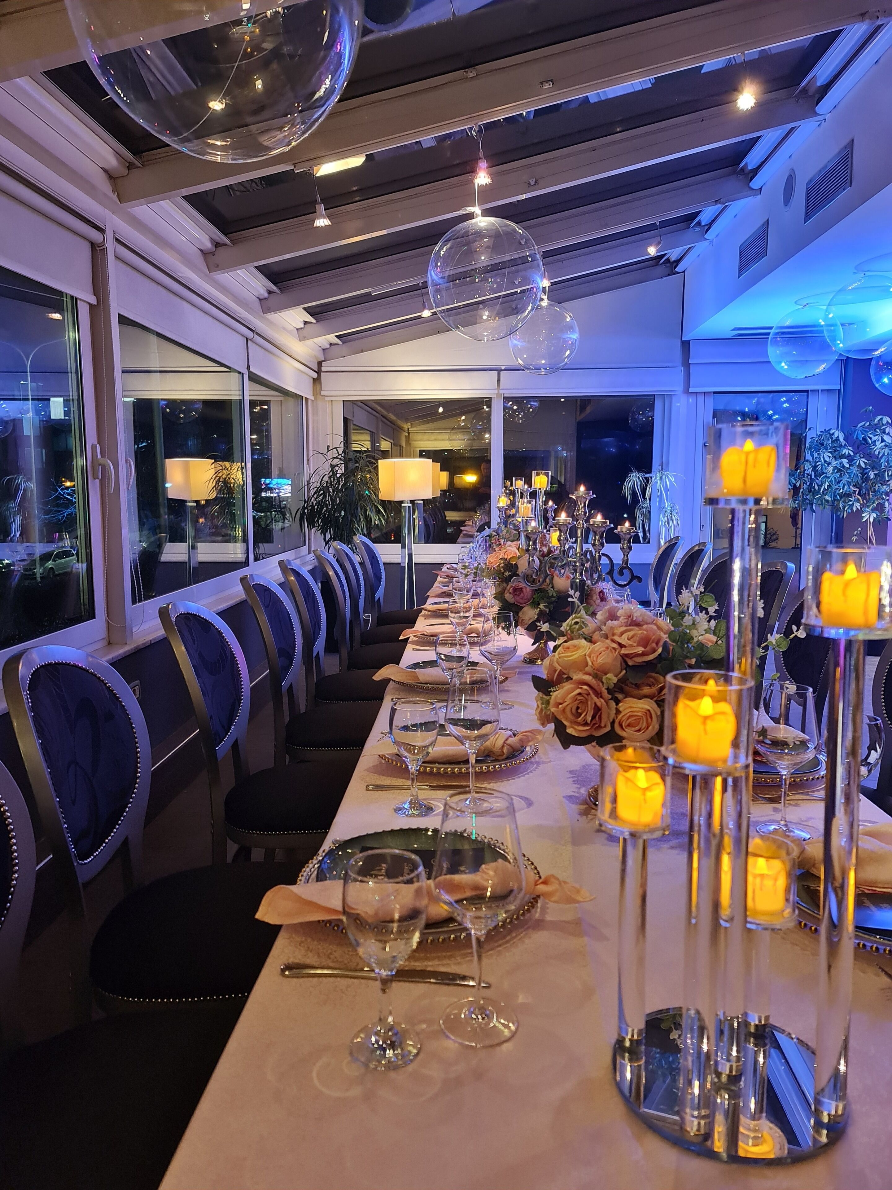 A long dining table with chairs, candles, and floral centerpieces.