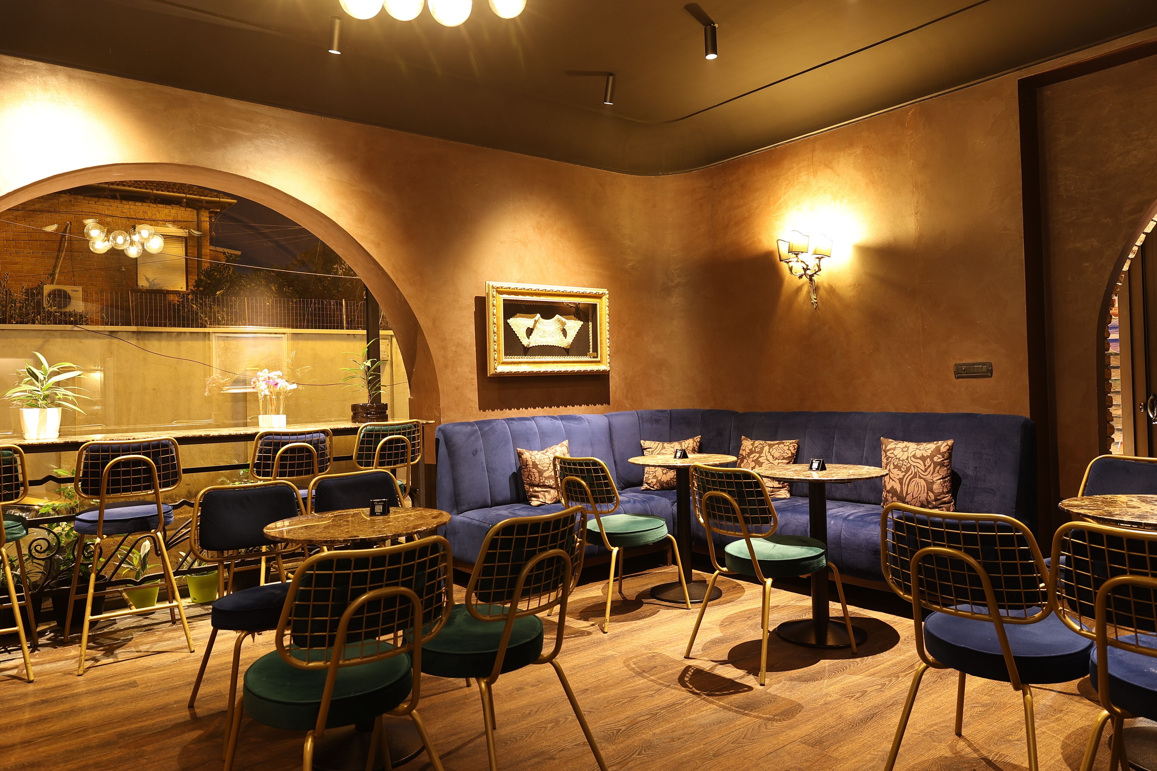 A cozy restaurant interior with a blue sofa, round tables, and metal chairs.