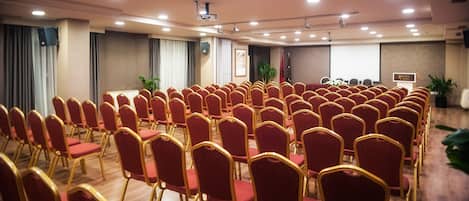 A conference room with rows of red chairs and a podium.