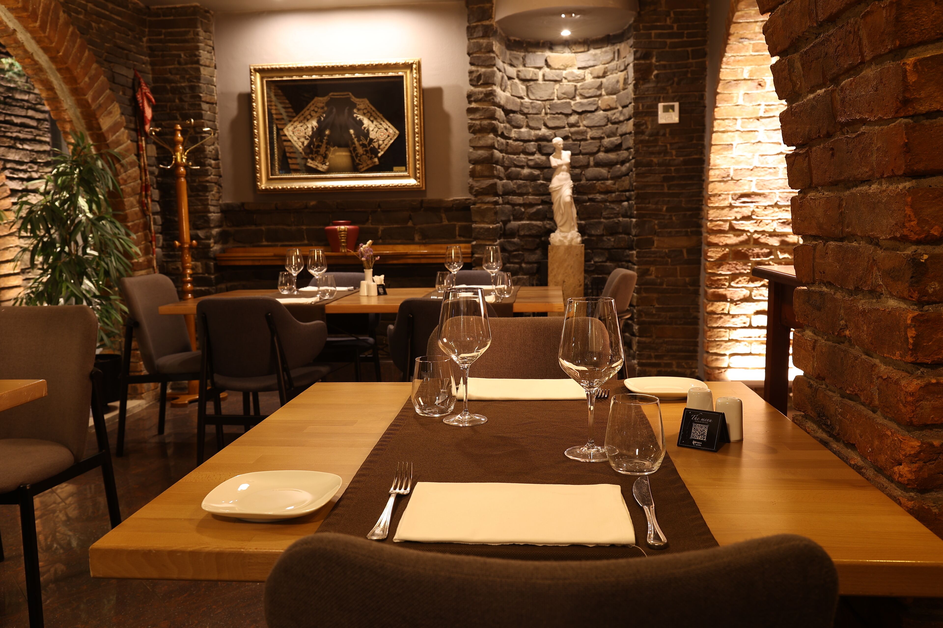 Ein Restaurant mit Backsteinwand, einem gerahmten Gemälde und einer Statue.