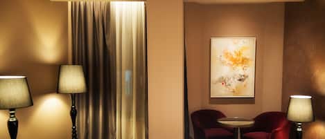 Une chambre d’hôtel avec un lit, deux lampes, une chaise, une table et un tableau au mur.
