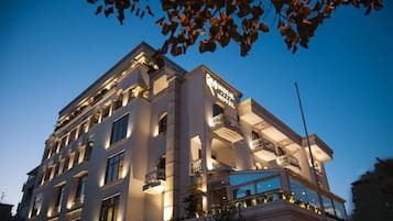 A multi-story hotel with a prominent sign reading "Mondial Hotel." The building features multiple balconies and large windows.