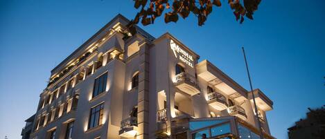 A multi-story hotel with a prominent sign reading "Mondial Hotel." The building features multiple balconies and large windows.