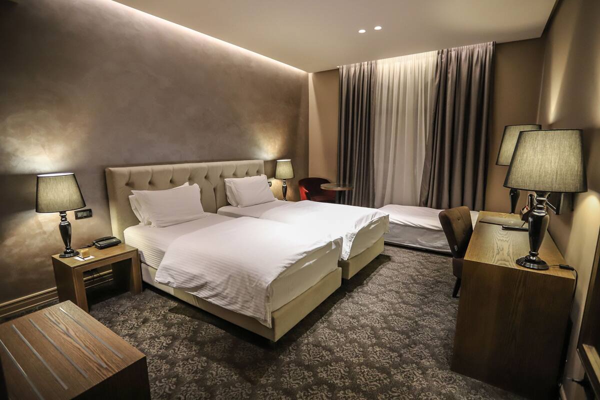 A hotel room with a large bed, bedside tables, a desk, and a chair.