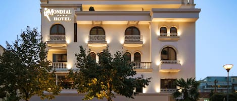 Un hotel con un cartel llamativo, varios balcones y una entrada bien iluminada.
