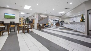 A spacious lobby with a reception desk, seating area, and a staircase. - Crossroads Hotel at Huron Event Center (Huron)