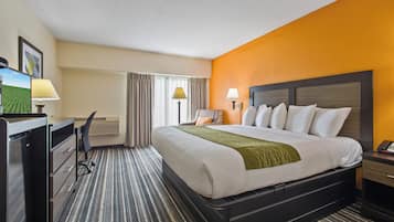 Habitación de hotel con cama, escritorio, silla y vista a un campo a través de la ventana.