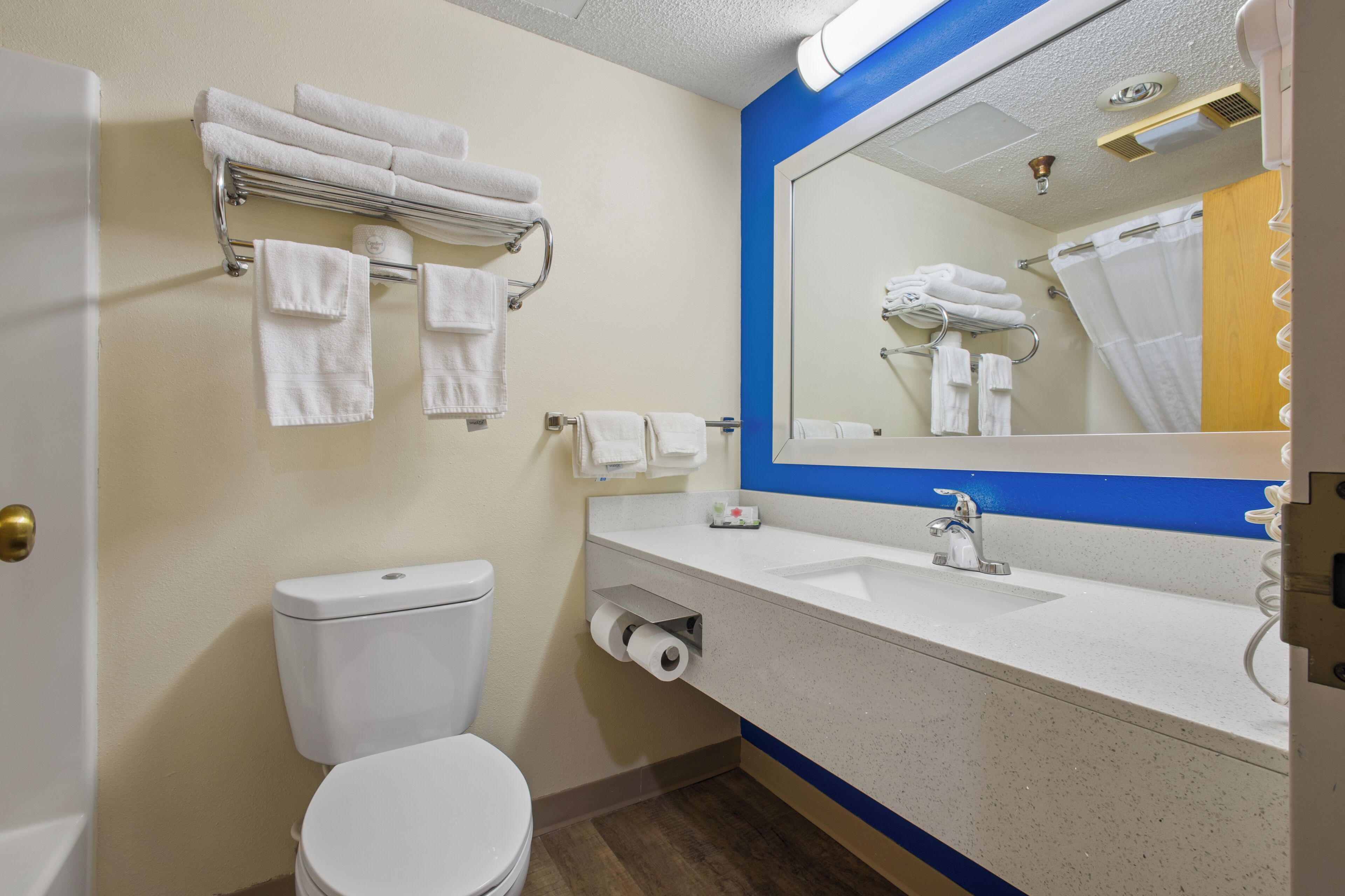 Ein Badezimmer mit Toilette, Waschbecken, Spiegel und Handtuchhalter.