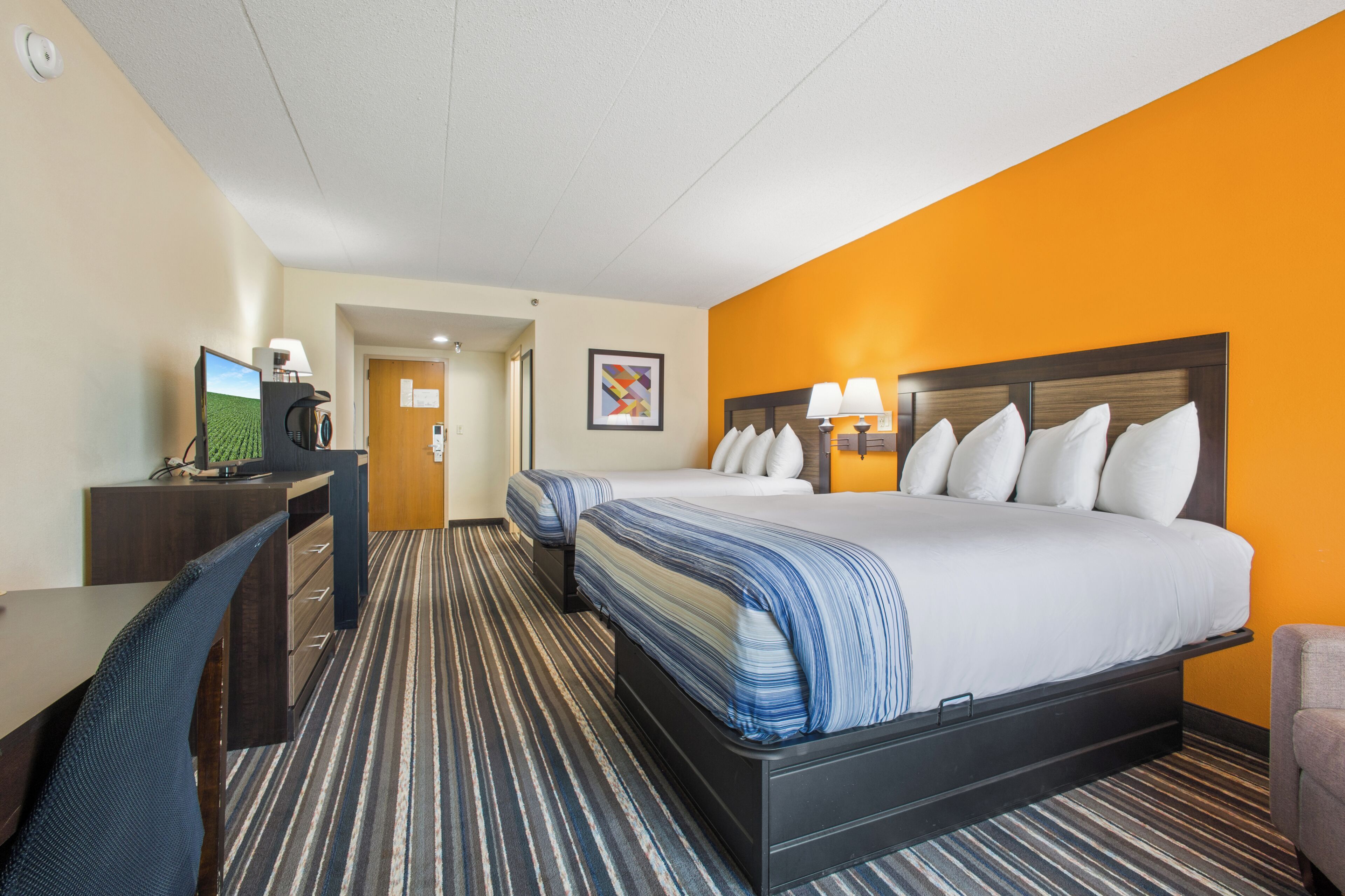 Une chambre d’hôtel équipée d’un lit, d’un bureau, d’une chaise et d’un téléviseur.