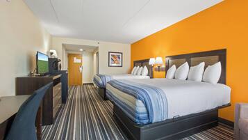 A hotel room with a bed, desk, chair, and a television.