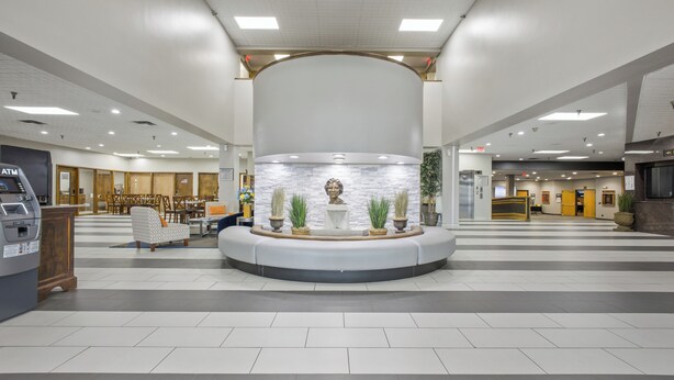 A spacious lobby with a central seating area, a reception desk, and an ATM machine. - Crossroads Hotel at Huron Event Center (Huron)