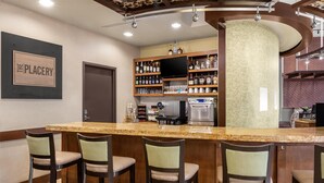 A bar area with a granite countertop, bar stools, a television, and a variety of liquor bottles. - Hyatt Place Memphis/Germantown (Memphis)