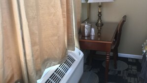 A hotel room with a sofa, a table with a lamp, a mirror, and a radiator. - Anchor Motel (Niagara Falls)