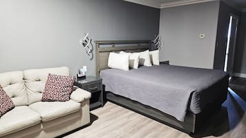 A bedroom with a bed, a sofa, a nightstand, and a wall-mounted light fixture.