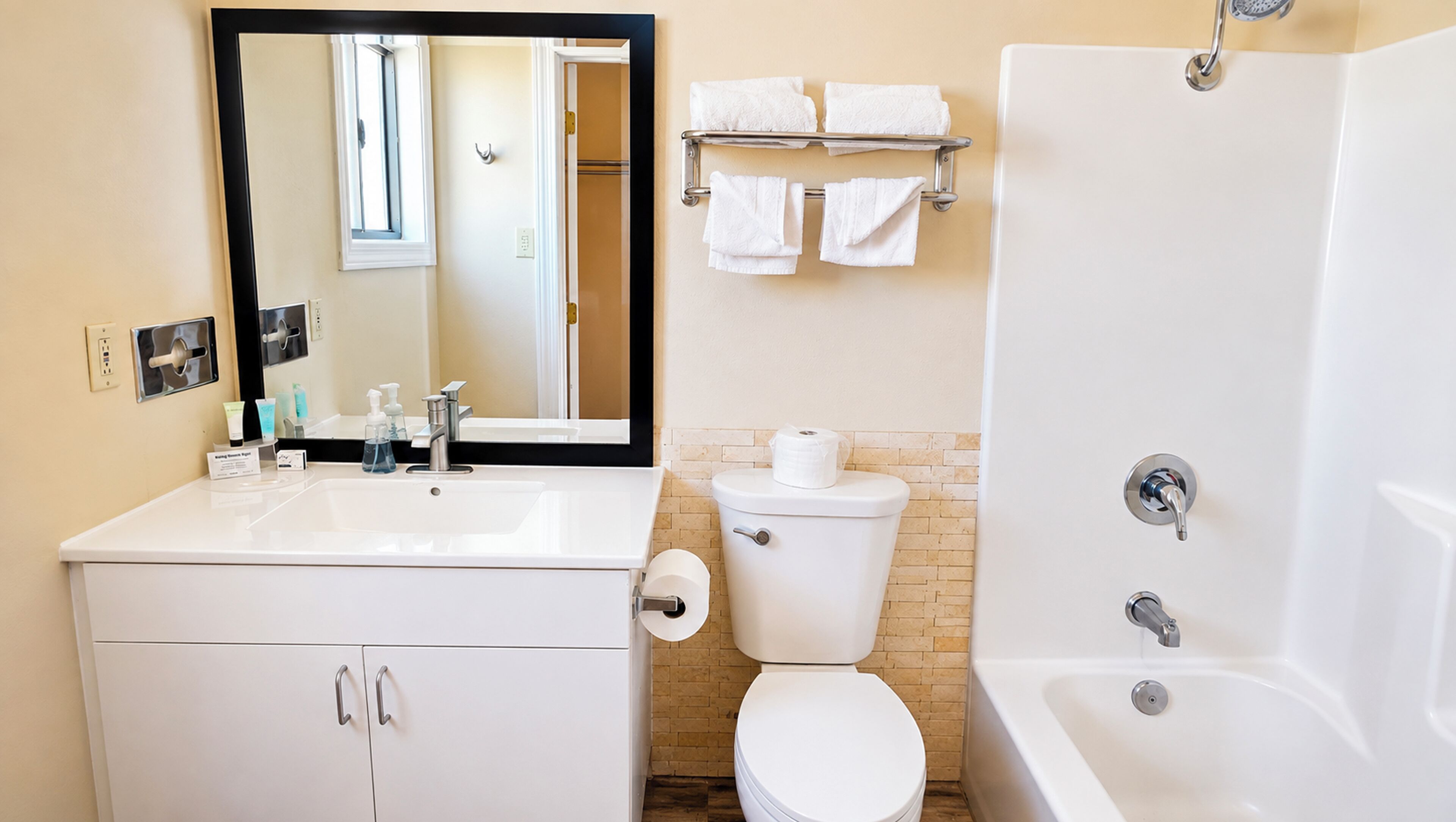 Une salle de bain avec un lavabo blanc, un miroir, des toilettes et une baignoire.