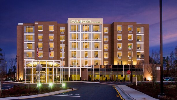 Un hotel con fachada moderna, varios pisos y una entrada destacada con puertas de vidrio.