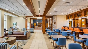 Un vestíbulo de hotel con zona de estar, bar y mostrador de recepción.