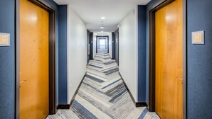 Un pasillo de hotel con pisos alfombrados, puertas de madera y un letrero que indica la habitación número 307.