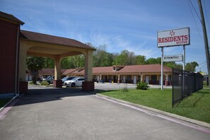 A hotel with a covered parking area, a sign for Residents Suites, and a sign for Kitchenettes.