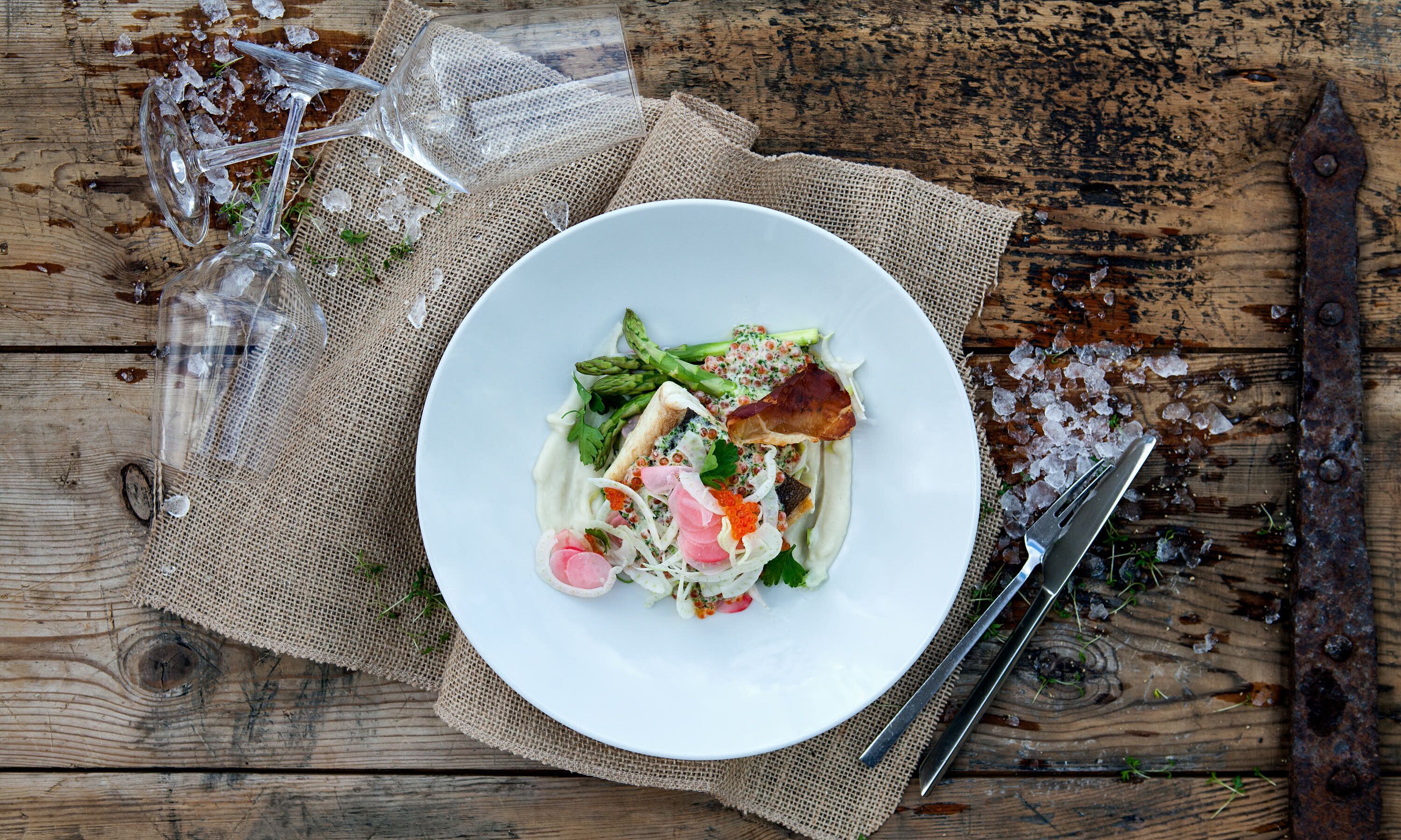 A white plate with a salad on a rustic wooden table.