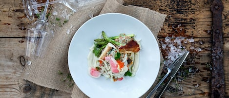 A white plate with a salad on a rustic wooden table.