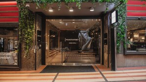 A hotel entrance with a glass door, a sign reading 'Folketeateret Home Hotel', and a large sculpture in the center. - Home Hotel Folketeateret (Oslo)