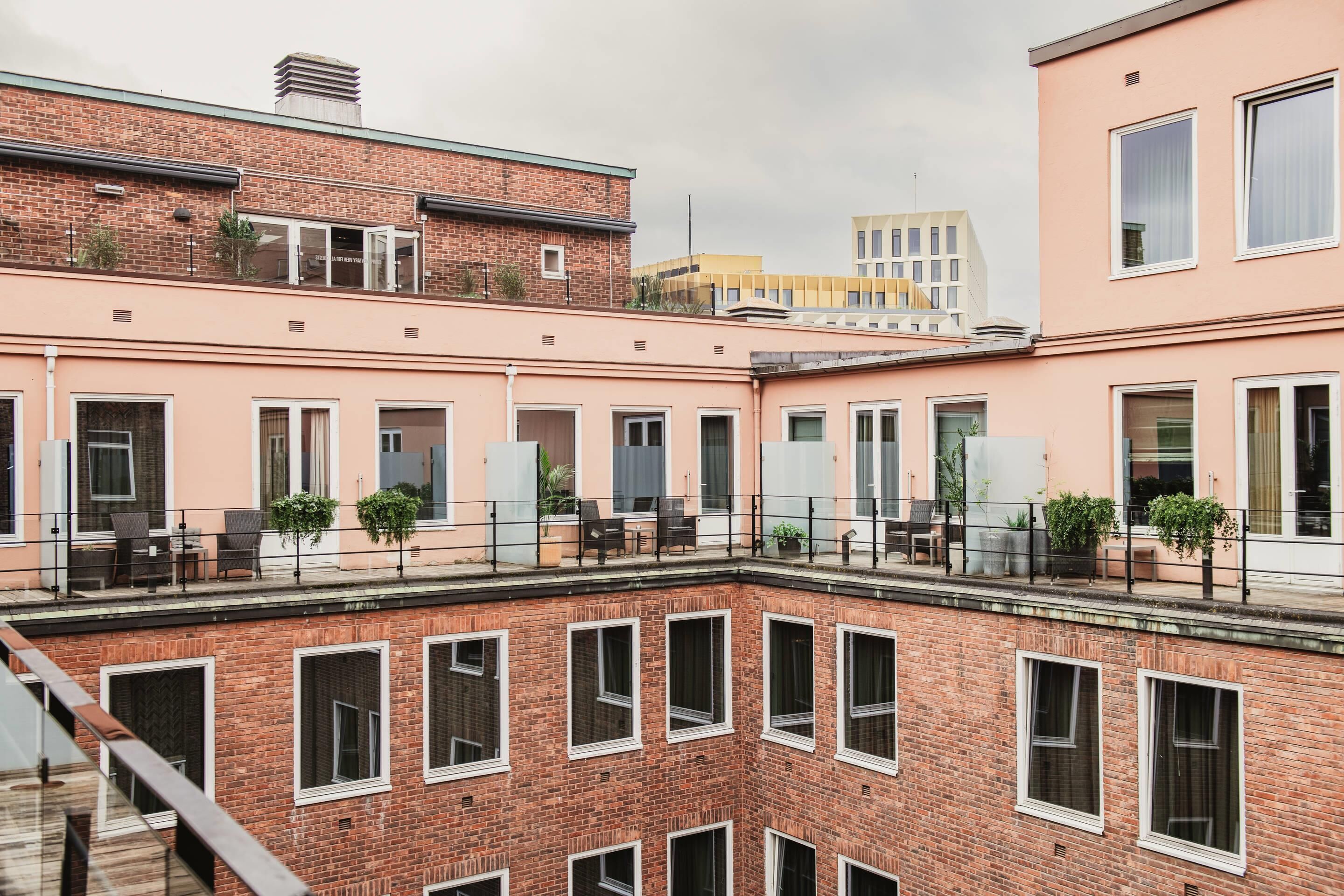 Un edificio de varios pisos con fachada de ladrillo, amplias ventanas y zonas de estar al aire libre.