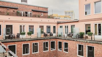 Un edificio de varios pisos con fachada de ladrillo, amplias ventanas y zonas de estar al aire libre.