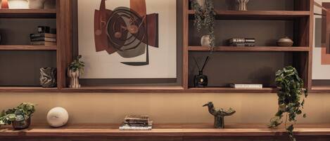 A modern interior with wooden shelves, a framed abstract artwork, and various decorative items.